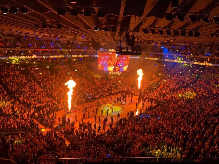 Crowd of people sitting on tribunes of spacious stage and watching performance with torches while celebrating game in modern sport place