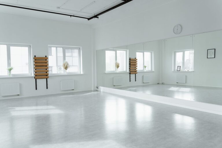 Spacious light-filled dance studio featuring large mirrors and minimalist decor.